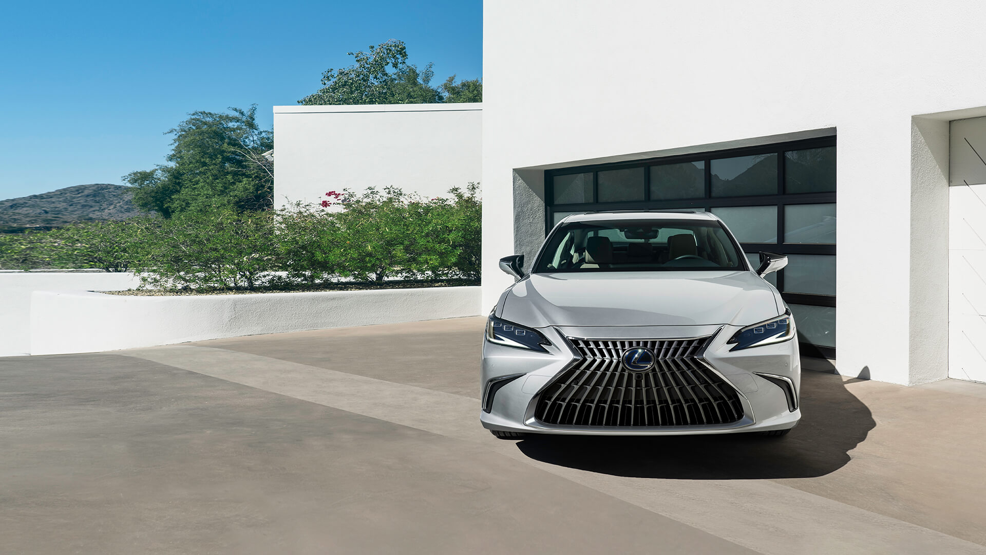 Silver Lexus ES is parked next to a white house.