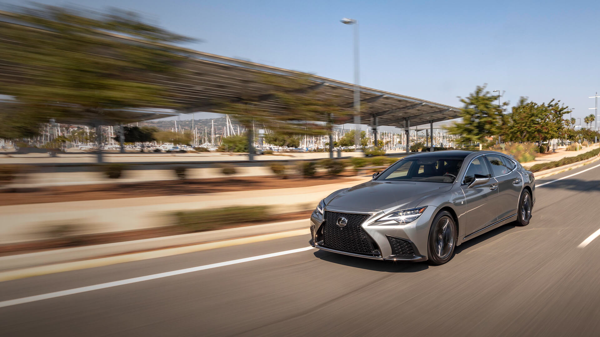 Silver Lexus LS being driven on sandy ground.