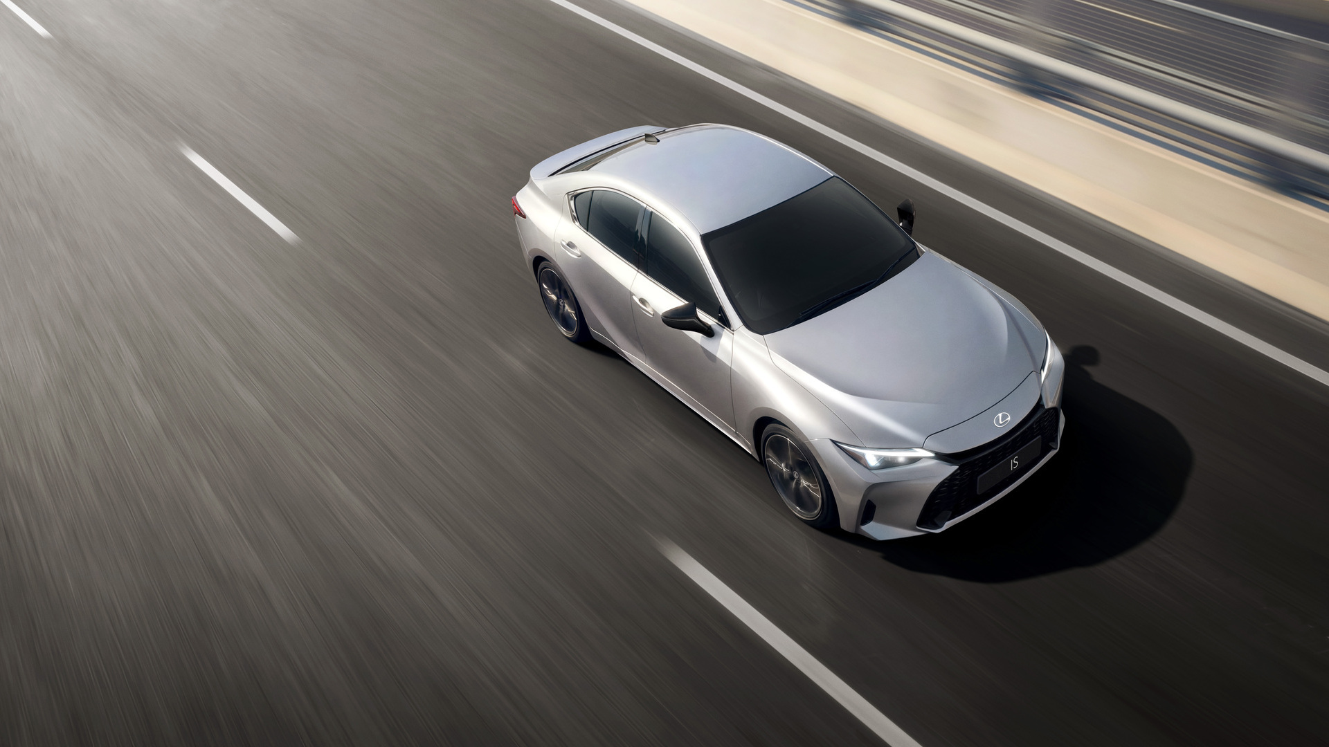 Silver Lexus IS being driven in a city.